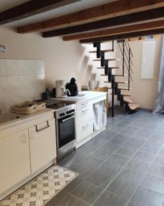 a kitchen with white cabinets and a staircase at l'Echappée Crançotine in Crançot