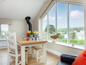a dining room with a table and chairs and windows at Meadowside in Saint Mawes