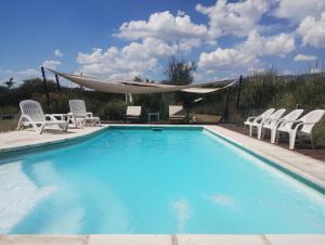 a large swimming pool with chairs and a hammock at La Celina Casas de Campo in Nono