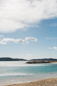 a beach with blue water and a cloudy sky at Hôtel Les Voiles in Toulon