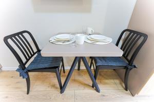 a white table with two chairs with plates and glasses at 1 room apartment CITY PLUS 2 in Almaty