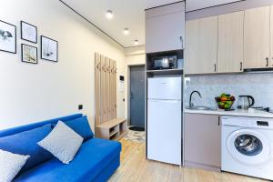 a living room with a blue couch and a kitchen at 1 room apartment CITY PLUS 2 in Almaty +5 photos