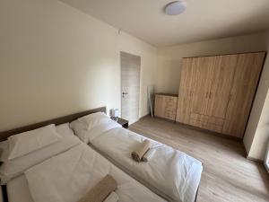 a bedroom with a large white bed with two towels on it at Sziget Apartmanház in Baja +7 photos