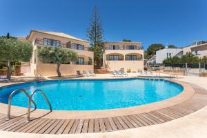 a swimming pool with chairs and a house in the background at Mar Hotels Alcanada in Port d'Alcudia