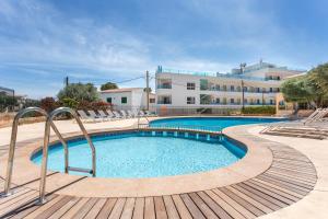 a swimming pool with chairs and a building in the background at Mar Hotels Alcanada in Port d'Alcudia