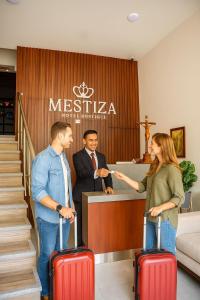a woman and two men with suitcases in front of a counter at Mestiza Hotel Boutique in Ipiales