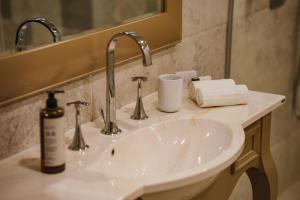 een wastafel met twee kranen en een spiegel bij Domeniile Martinutzi - Hotel Cardinal in Alba Iulia +55 foto's