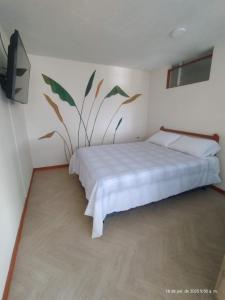 a bedroom with a bed with a plant on the wall at El Jardín cerca Aeropuerto de Pasto, comodidad y descanso in Chachagüí