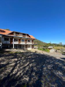 a large house on the beach with a dirt road at Pousada Saint Claire in Santo Antônio do Pinhal