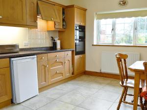 a kitchen with wooden cabinets and a white dishwasher at Alby Bungalow in Wetheral