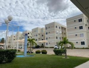 a large building with palm trees in a parking lot at Apartamento Moderno & Mobiliado - Próximo ao Aeroporto, Condomínio Village Natureza in Juazeiro do Norte