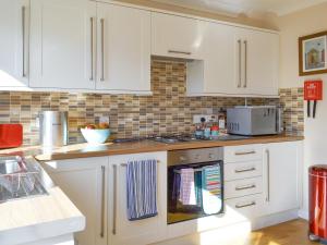 a kitchen with white cabinets and a stove top oven at Signals Court in Scarborough
