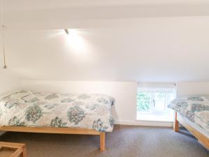 a bedroom with two beds and a window at Broom Cottage in East Rudham