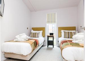 two beds in a room with white walls at Cheddar Woods Resort And Spa in Cheddar