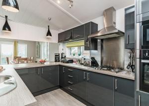 a large kitchen with black cabinets and a sink at Cheddar Woods Resort And Spa in Cheddar