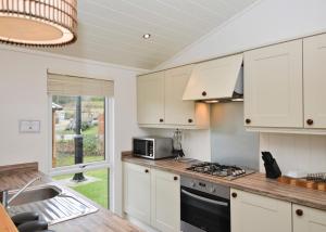 a kitchen with white cabinets and a stove top oven at Cheddar Woods Resort And Spa in Cheddar