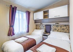 a small room with two beds and a window at Cheddar Woods Resort And Spa in Cheddar