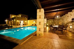 a swimming pool with a table and chairs next to a house at Villa-Aristotelis in Gerani