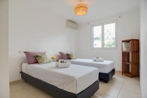 two beds in a room with white walls at Villa Célestine in Saint-Paul