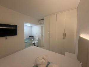 una stanza con un letto con una TV e mobili bianchi di APT Luxo 4 SUITES ONDINA Circuito CARNAVAL a Salvador