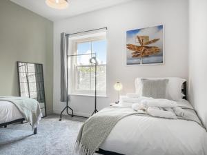 a white bedroom with a bed and a window at Pavilion Mews in Buxton