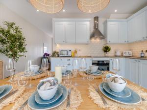 a kitchen with a table with plates and glasses on it at Ty Mor in Abersoch +11 photos