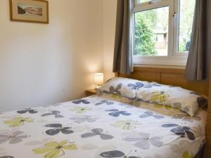 ein Schlafzimmer mit einem Bett mit geblümtem Laken und einem Fenster in der Unterkunft Chalet 2 - Uk12562 in Mount Hawke
