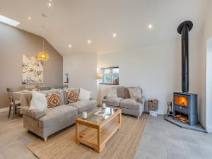 Una sala de estar con un sofá y una chimenea. en Y Beudy Gwydir, en Trevor