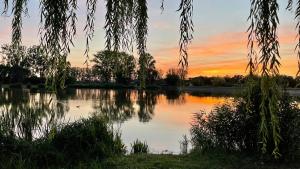 a view of a lake with a sunset in the background at Villa Limhamn - Őrbottyán in Őrbottyán