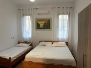 two beds in a room with two windows at Seid Apartments Radhime in Vlorë