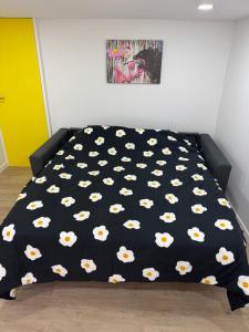 a bed with a black comforter with white cows on it at Studio Confort by Titou - Jumet in Charleroi