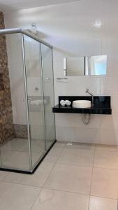 a bathroom with a glass shower and a sink at POUSADA CAJU DO MATO in Prado
