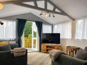 a living room with a flat screen tv and chairs at Lake View Cottage in Belper