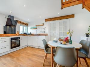 a kitchen with white cabinets and a table and chairs at Horseshoe Cottage - Uk48252 in Downderry