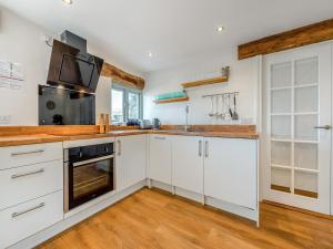 a kitchen with white cabinets and a sink at Horseshoe Cottage - Uk48252 in Downderry