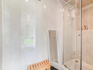 baño blanco con ducha y banco en Shadi - Uk45069, en Derwydd 4 fotos más
