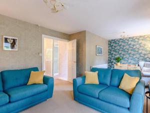 a living room with two blue couches and a door at Cherry Tree Corner in Ashbourne