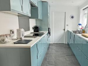 eine Küche mit blauen Schränken und weißen Arbeitsplatten in der Unterkunft Poppy Cottage in Eryholme