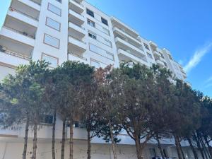a tall white building with trees in front of it at Skampini Qerret Apartments in Golem