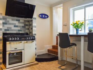 a kitchen with a stove and a counter with chairs at Pilchard Cottage in Scarborough +14 photos