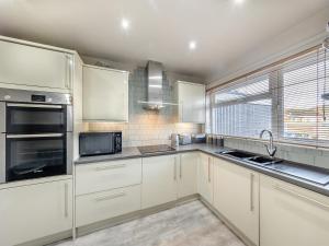 eine weiße Küche mit weißen Schränken und einem Fenster in der Unterkunft House In The Hills in Church Stretton