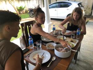 Un gruppo di persone seduti intorno a un tavolo che mangiano cibo di 360 Lotus Hostel Tangalle and Cowork a Tangalle
