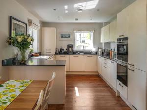 a kitchen with white cabinets and a table with a vase of flowers at Torrance At Abbey Park Avenue in St. Andrews