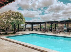 a swimming pool with tables and chairs and a patio at Flat no Hotel Monte Castelo in Sairé