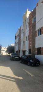 Dos coches estacionados en un estacionamiento al lado de un edificio. en une chambre, un salon, cuisine et balcon, en Monastir