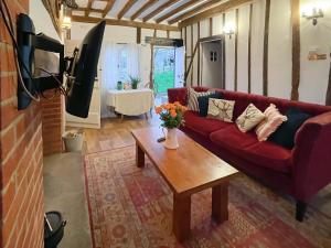 a living room with a red couch and a coffee table at The Cottage At Harple Farm in Detling