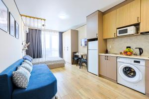 a living room with a blue couch and a kitchen at 1 room apartment CITY PLUS 3 in Almaty