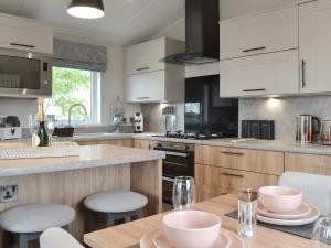 a kitchen with white cabinets and a table with chairs at Peacock - Uk31513 in Calthwaite +17 photos