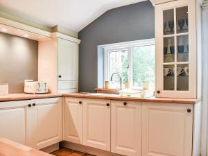 a kitchen with white cabinets and a window at Chapel Cottage in Robin Hood's Bay +9 photos