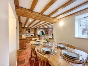 eine Küche und ein Esszimmer mit einem langen Tisch und Stühlen in der Unterkunft Gladwyn Cottage in Sutton Benger